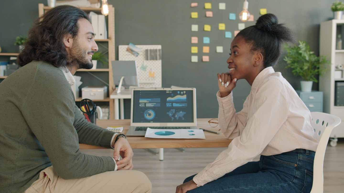 Two colleagues discussing work at a desk.