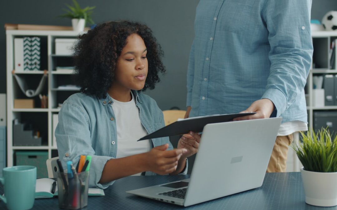 Two colleagues reviewing documents at an office desk.