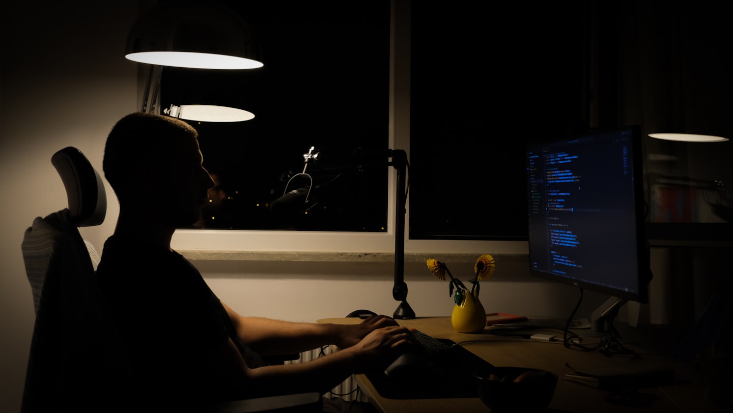 a man sitting in front of a computer in a dark room