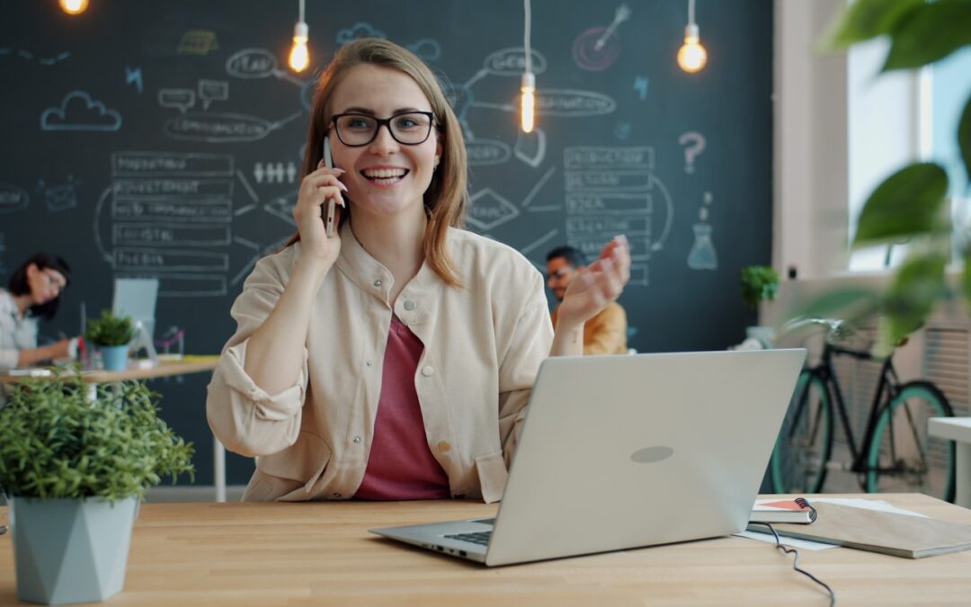 Smiling woman talking on phone in modern office