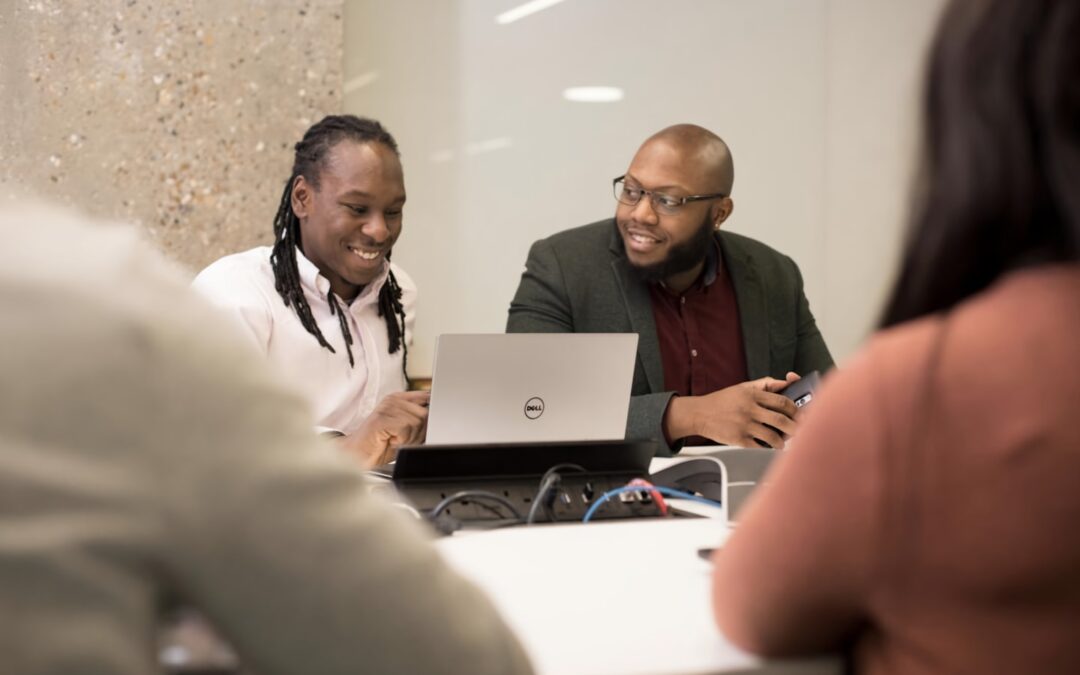 a group of people sitting around a laptop computer