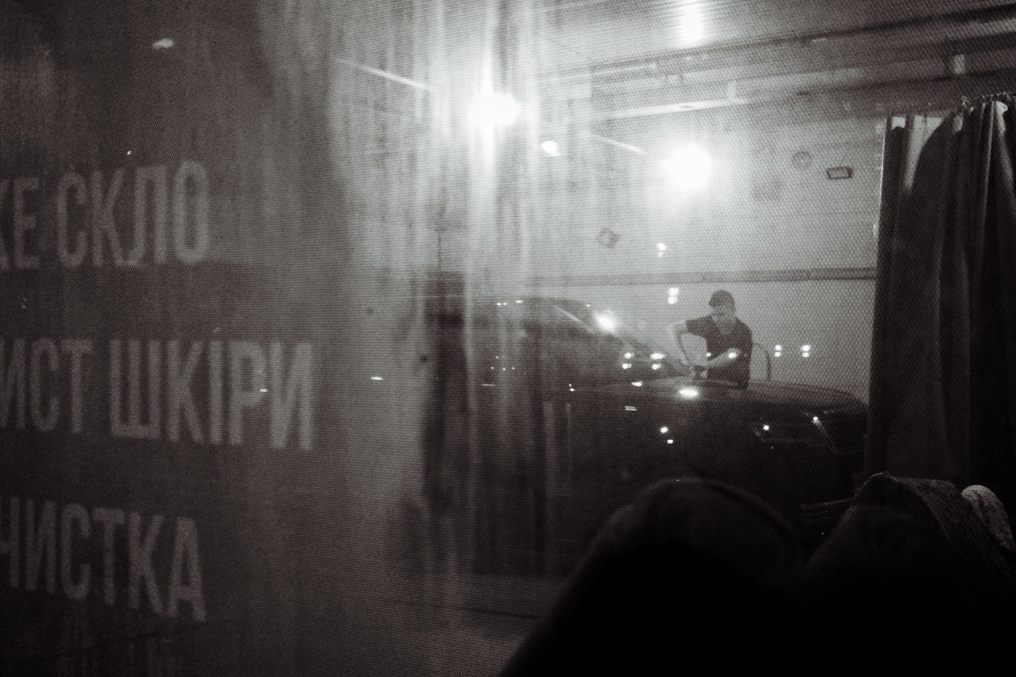 Man washing car in a dimly lit garage