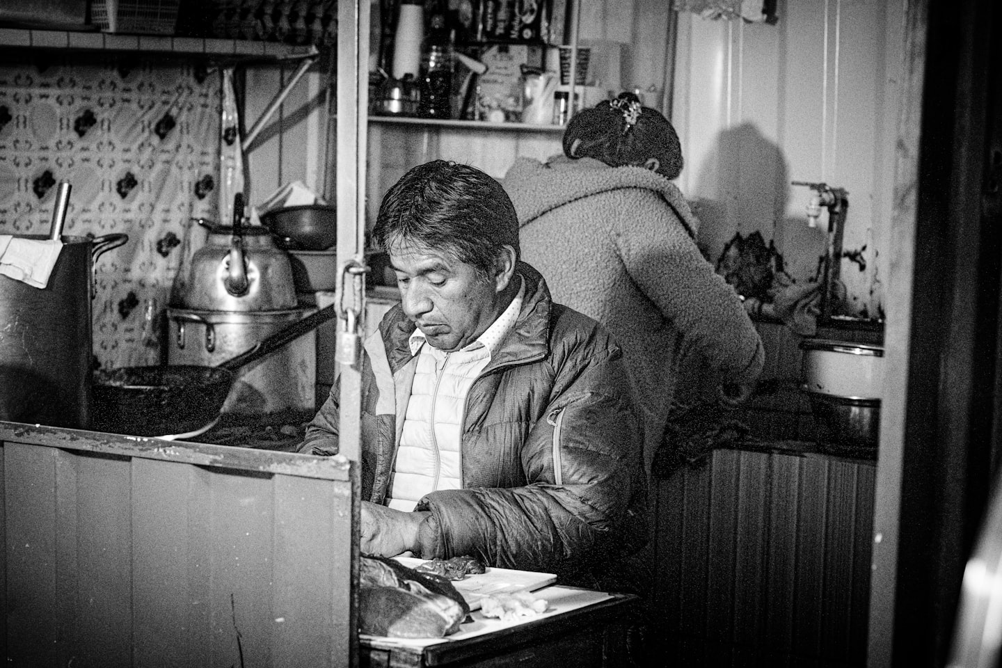 A black and white photo of a man working in a kitchen