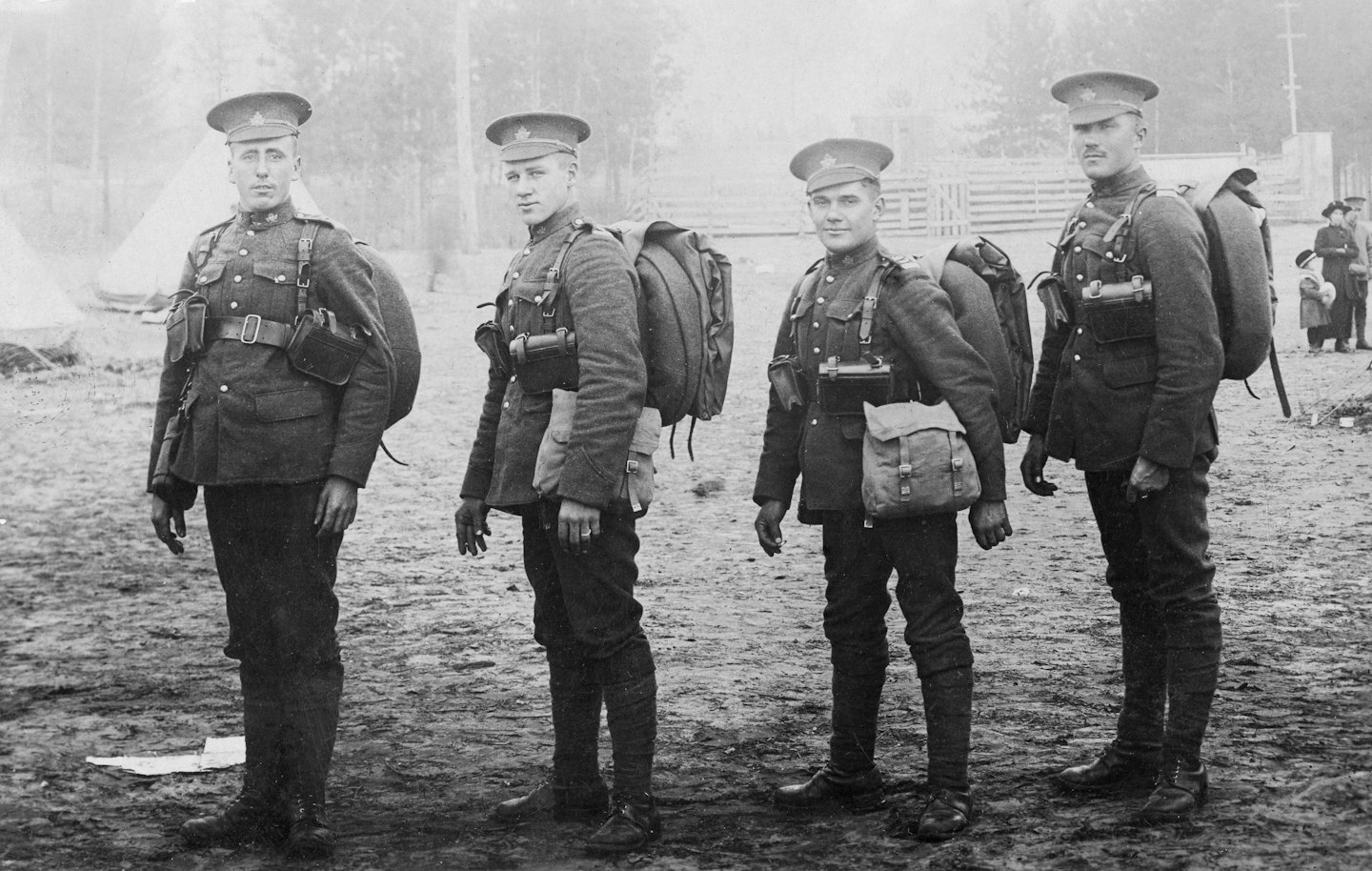 Four soldiers in uniform with backpacks stand together
