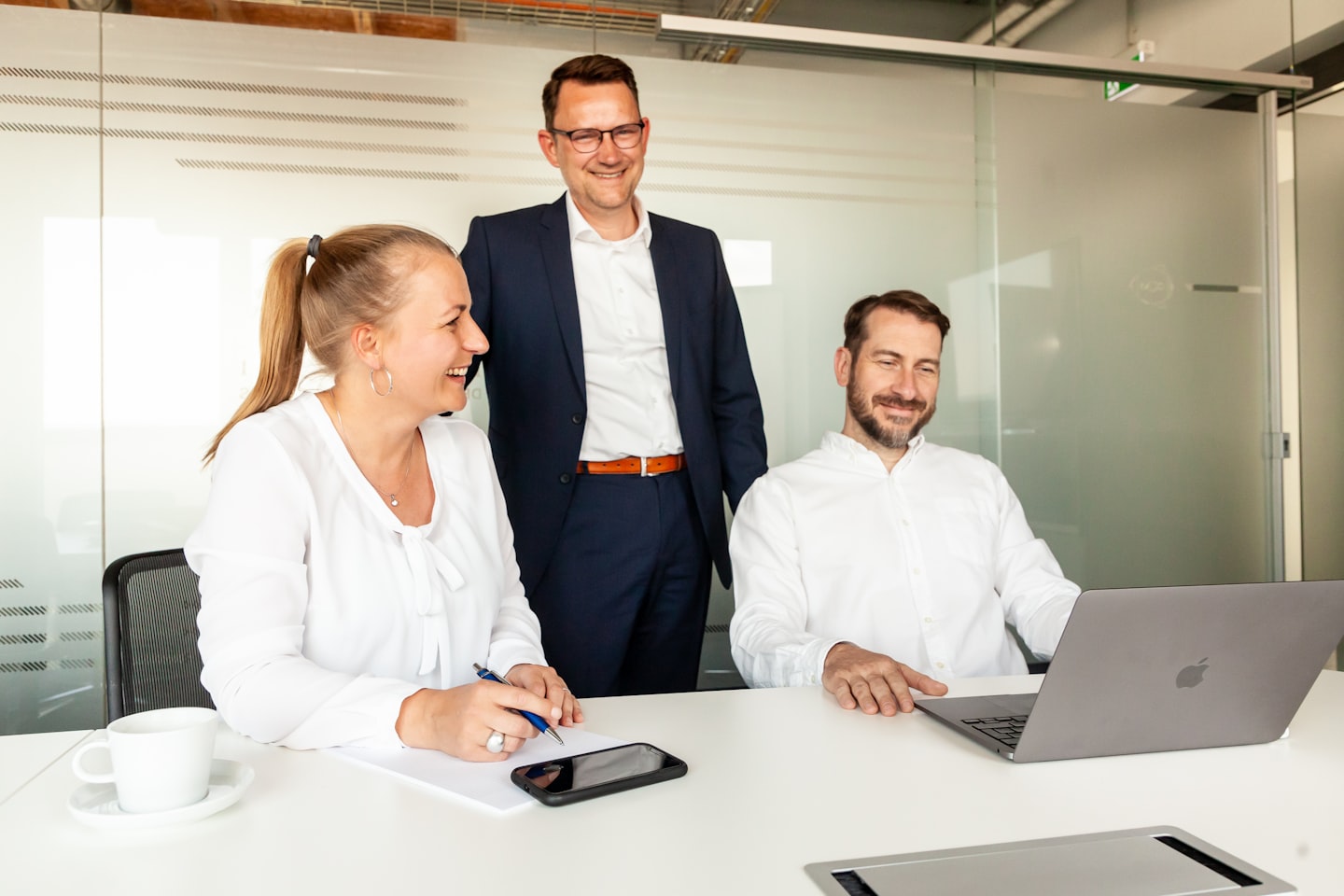 Three colleagues collaborating around a laptop in an office