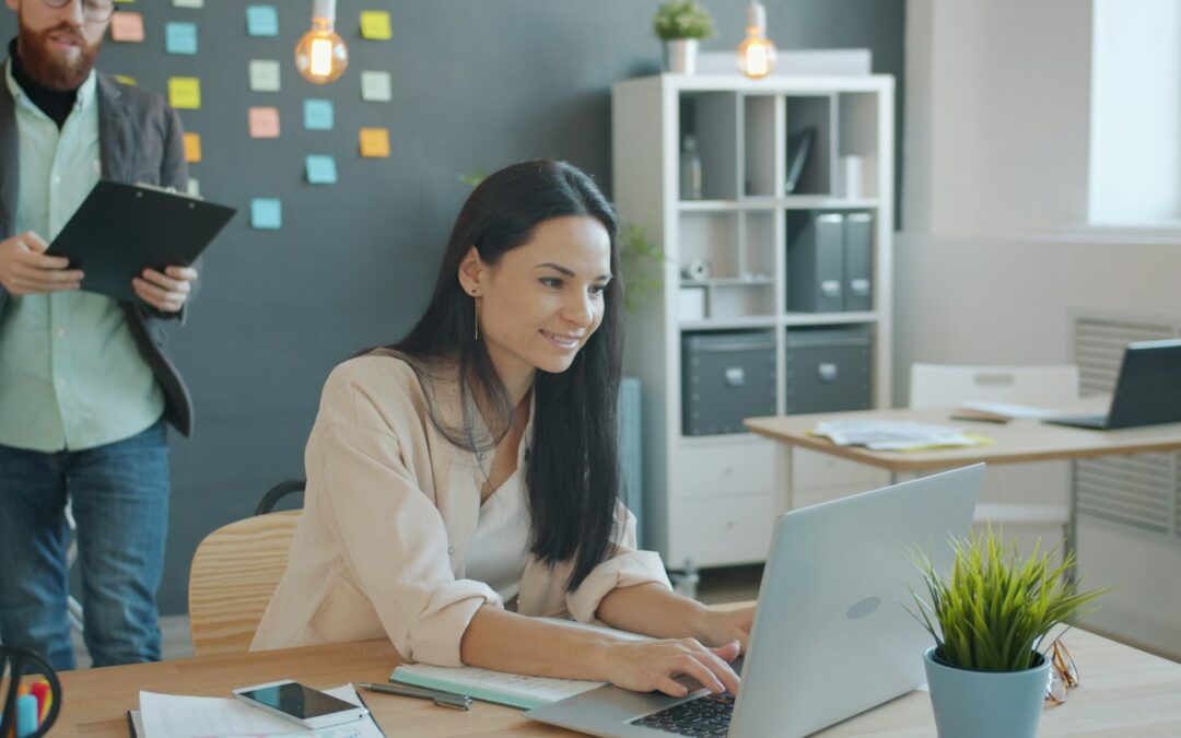 Woman working on laptop with man behind her