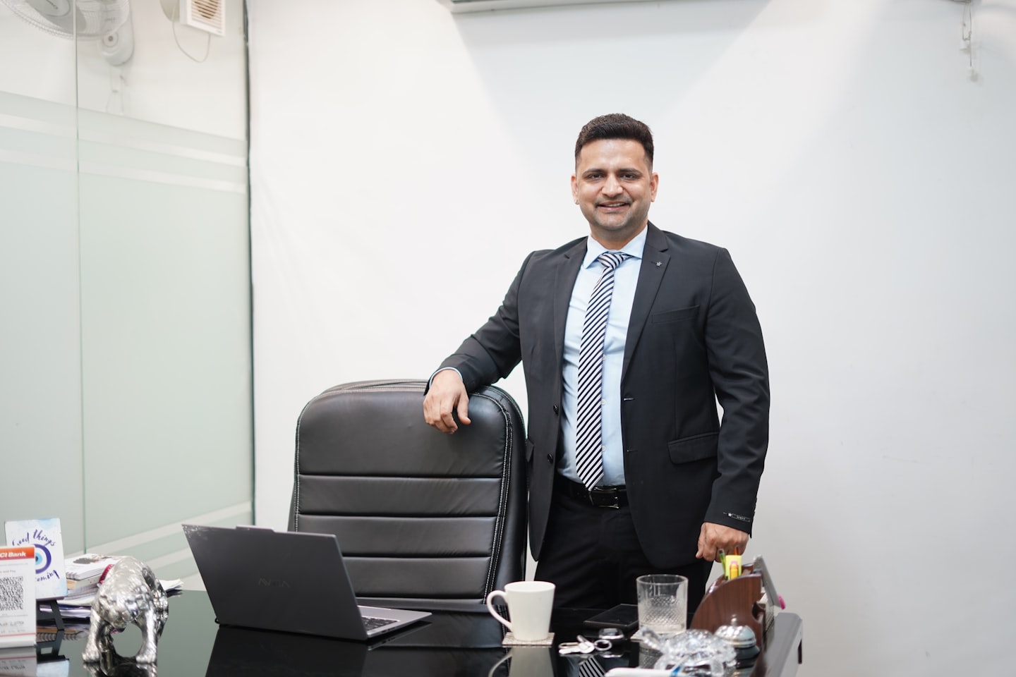 A man in a suit stands behind an office desk